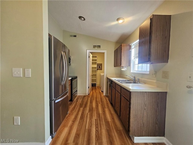 kitchen featuring visible vents, light countertops, lofted ceiling, stainless steel appliances, and a sink