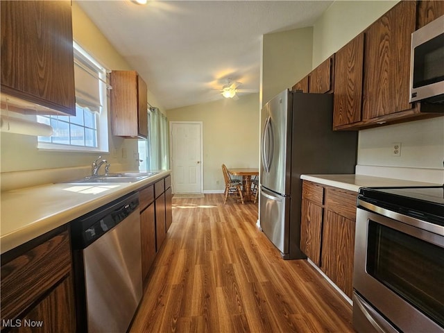 kitchen with light countertops, lofted ceiling, appliances with stainless steel finishes, light wood-style floors, and a sink