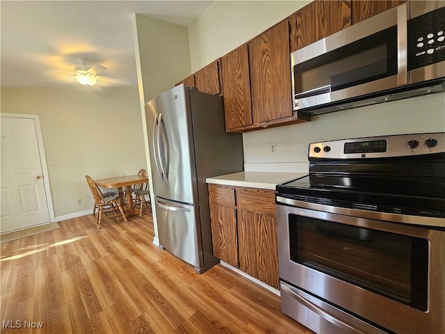 kitchen featuring brown cabinets, light wood-style flooring, appliances with stainless steel finishes, light countertops, and ceiling fan