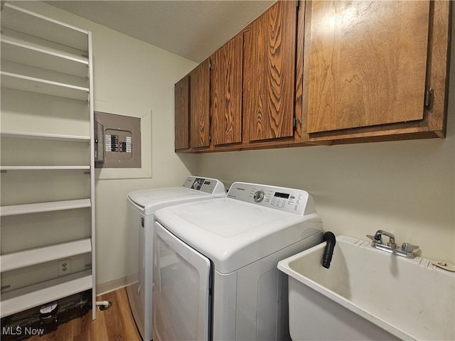 laundry room with a sink, electric panel, wood finished floors, cabinet space, and separate washer and dryer