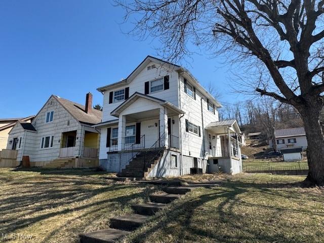 view of front of house featuring a porch, a front yard, and fence