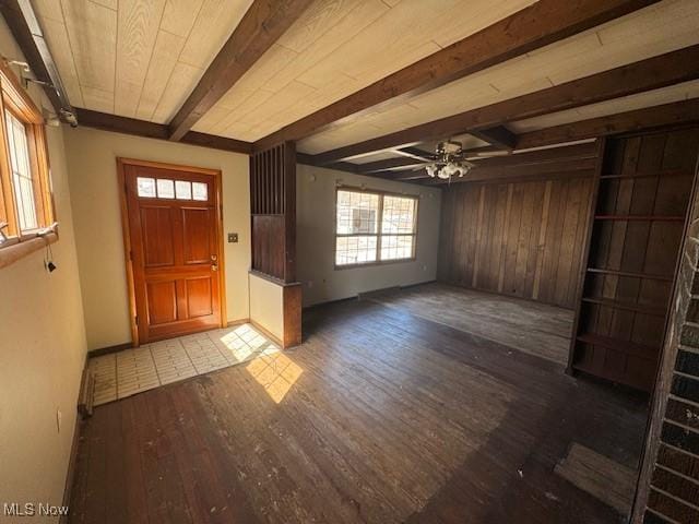 foyer entrance with beamed ceiling, wood walls, ceiling fan, and wood finished floors