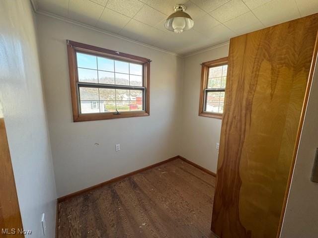 unfurnished room featuring baseboards, wood finished floors, and ornamental molding