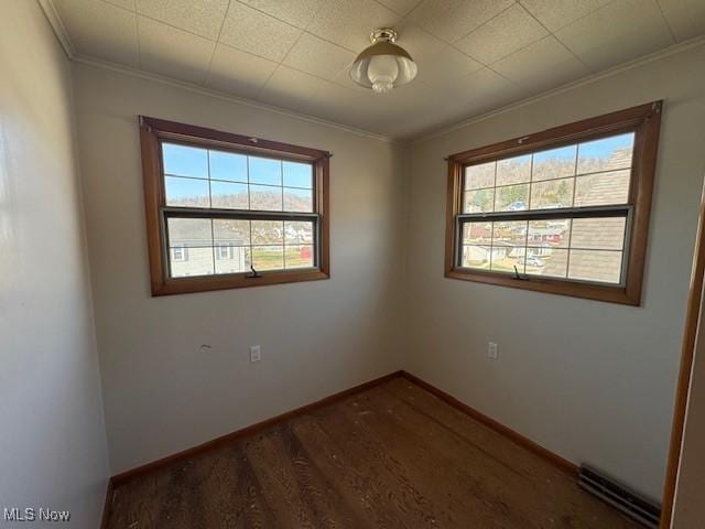 spare room with wood finished floors, a healthy amount of sunlight, visible vents, and ornamental molding