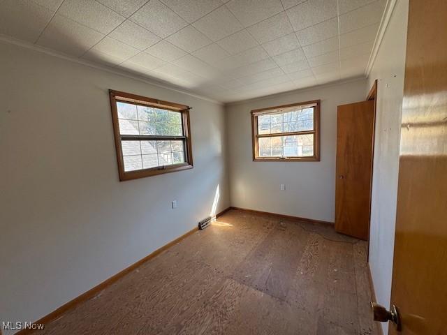 unfurnished room with baseboards and crown molding