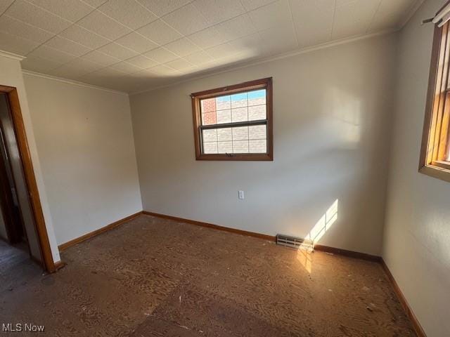 spare room with visible vents, baseboards, and ornamental molding