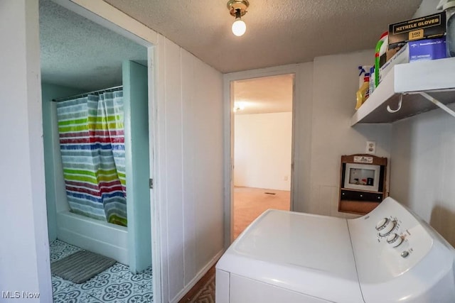 washroom featuring a textured ceiling, washing machine and dryer, and laundry area