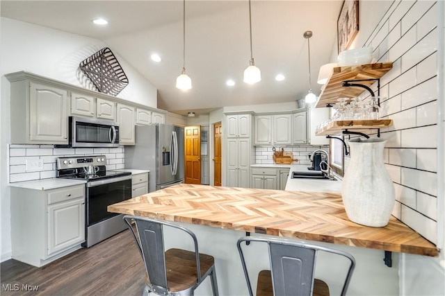 kitchen with a sink, open shelves, a kitchen breakfast bar, appliances with stainless steel finishes, and a peninsula