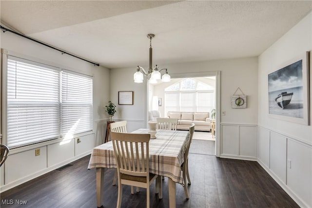 dining area featuring a notable chandelier, plenty of natural light, and dark wood-style flooring