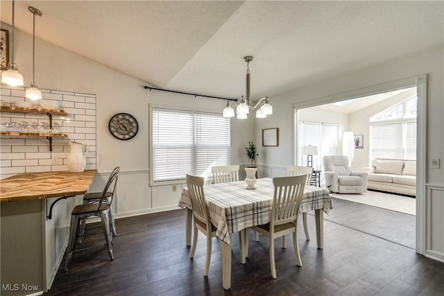 dining area featuring a notable chandelier, baseboards, lofted ceiling, and dark wood-style flooring