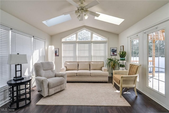 living area with baseboards, lofted ceiling with skylight, dark wood finished floors, and a ceiling fan