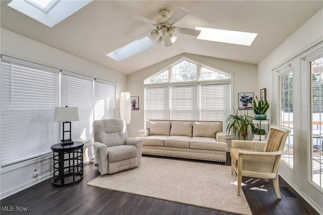 living room featuring dark wood-type flooring, vaulted ceiling with skylight, baseboards, and ceiling fan