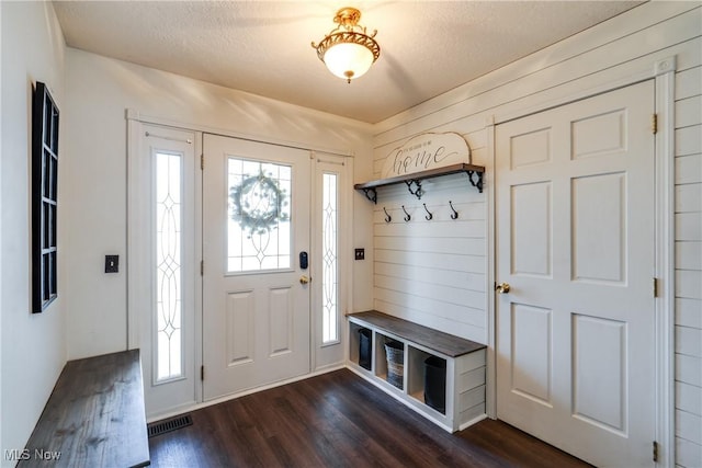 mudroom with dark wood-type flooring, visible vents, and a textured ceiling