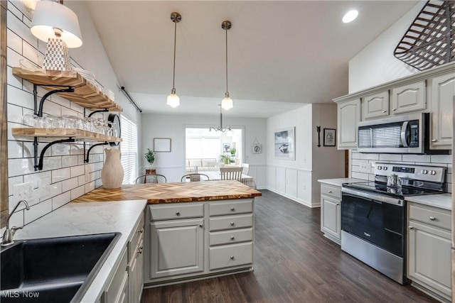 kitchen with open shelves, dark wood finished floors, a peninsula, stainless steel appliances, and a sink