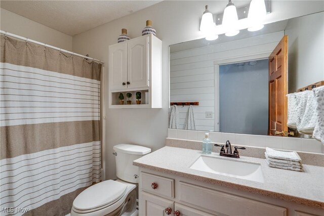 bathroom featuring a shower with shower curtain, toilet, and vanity