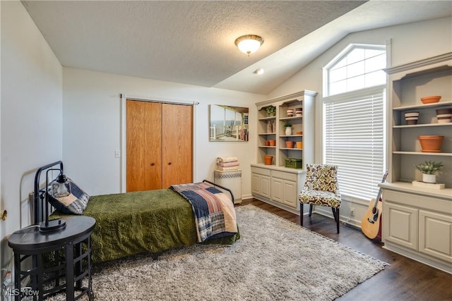 bedroom with vaulted ceiling, dark wood-style flooring, and a textured ceiling