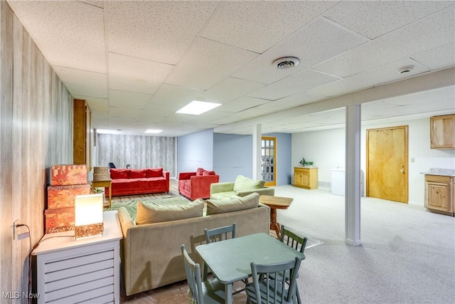 living area featuring light colored carpet, a paneled ceiling, visible vents, and baseboards