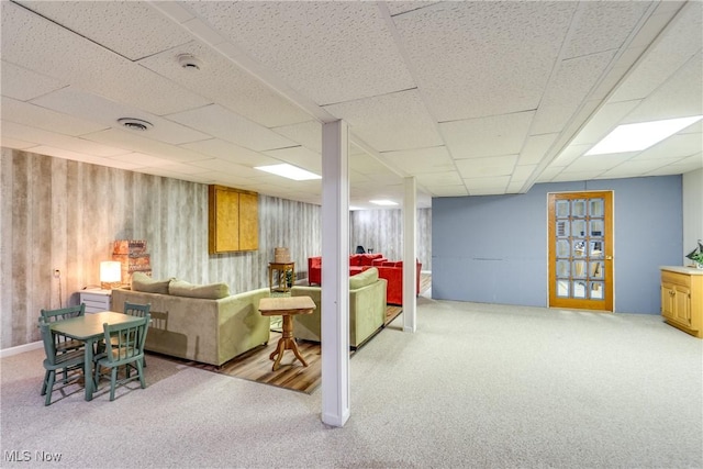 carpeted living area featuring a paneled ceiling, visible vents, and wood walls