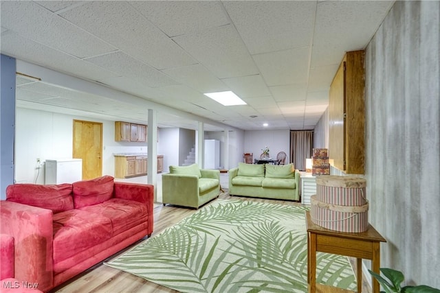 living room with light wood-style flooring and a paneled ceiling