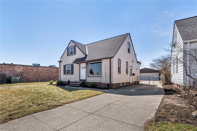 view of front of home with an outbuilding, fence, roof with shingles, a front lawn, and a garage