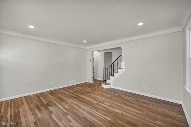 spare room with baseboards, stairs, recessed lighting, wood finished floors, and arched walkways