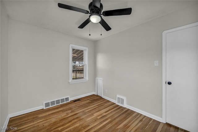 empty room featuring wood finished floors, visible vents, and baseboards