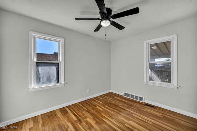 spare room with a wealth of natural light, visible vents, and wood finished floors