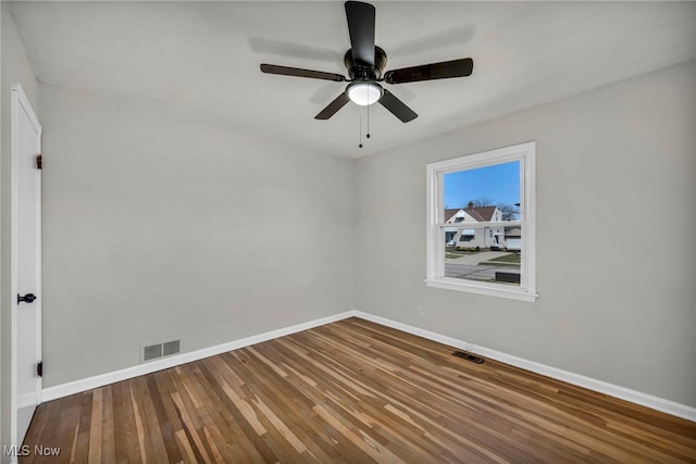 empty room featuring ceiling fan, wood finished floors, visible vents, and baseboards