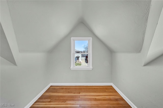 additional living space featuring vaulted ceiling, baseboards, and wood finished floors