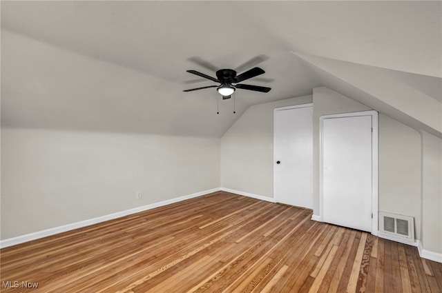 additional living space with baseboards, visible vents, light wood-style flooring, ceiling fan, and vaulted ceiling