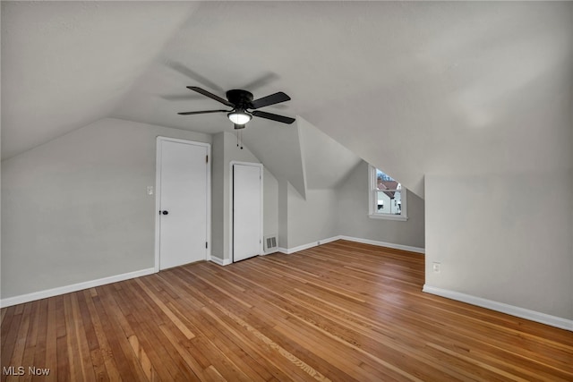 additional living space featuring visible vents, baseboards, lofted ceiling, ceiling fan, and hardwood / wood-style flooring