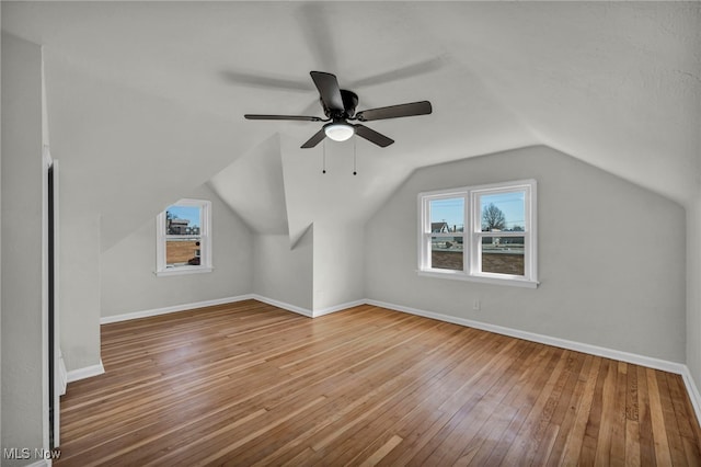 additional living space with vaulted ceiling, a ceiling fan, baseboards, and wood-type flooring