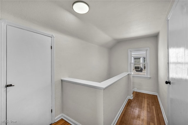 hallway featuring an upstairs landing, vaulted ceiling, baseboards, and hardwood / wood-style floors