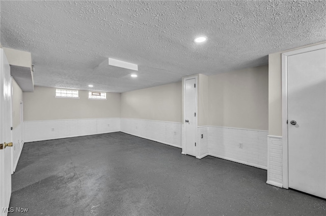 basement featuring a wainscoted wall and a textured ceiling