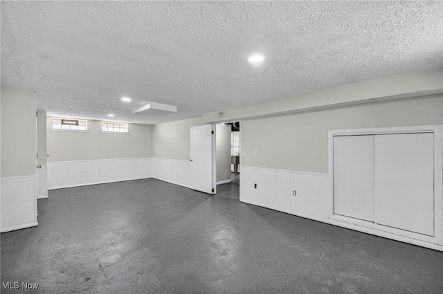 basement with a wainscoted wall and a textured ceiling