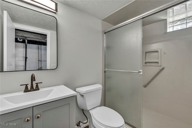 full bath with toilet, a stall shower, vanity, and a textured ceiling