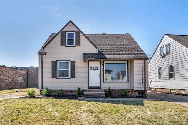 bungalow-style home featuring roof with shingles and a front yard