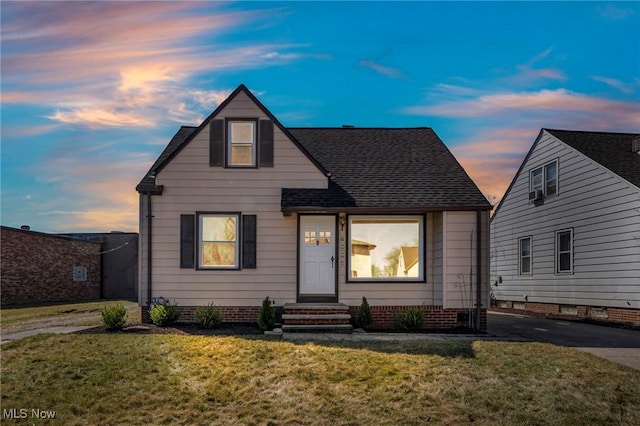 bungalow-style home with a shingled roof and a front yard