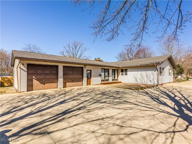 ranch-style house featuring concrete driveway, fence, a garage, and a chimney