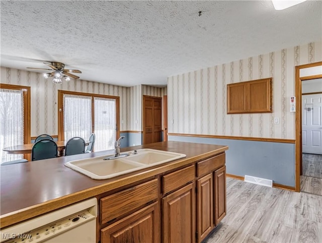 kitchen featuring visible vents, wallpapered walls, light wood-style flooring, a sink, and dishwasher