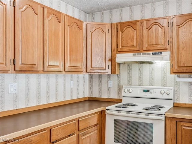 kitchen featuring electric range, under cabinet range hood, wallpapered walls, a textured ceiling, and light countertops