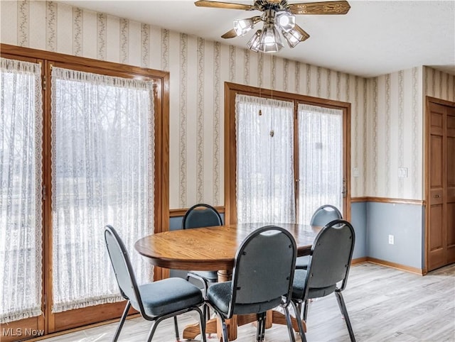 dining space with light wood finished floors, baseboards, a ceiling fan, and wallpapered walls