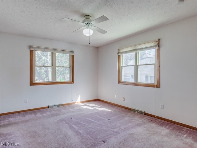 spare room featuring visible vents, a textured ceiling, ceiling fan, and carpet floors