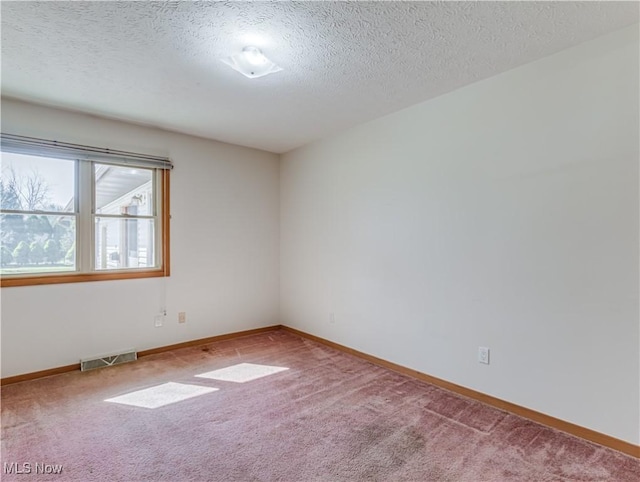 unfurnished room with visible vents, carpet floors, a textured ceiling, and baseboards