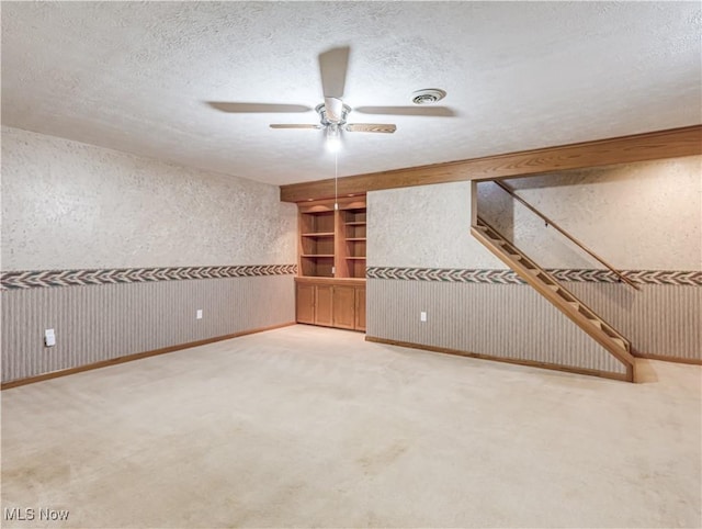 interior space featuring visible vents, a ceiling fan, a textured ceiling, carpet flooring, and stairs