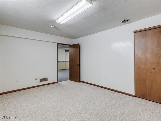 unfurnished bedroom featuring baseboards, visible vents, carpet floors, and a textured ceiling