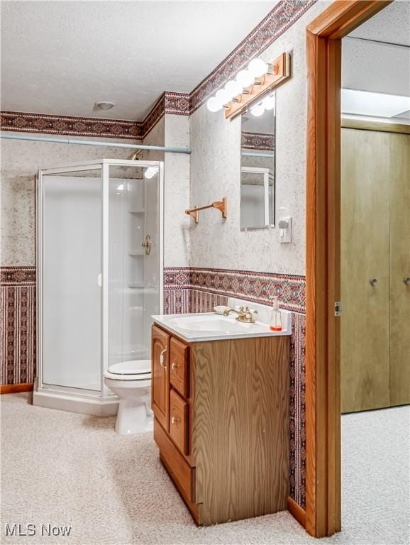 full bathroom with a wainscoted wall, a shower stall, and wallpapered walls