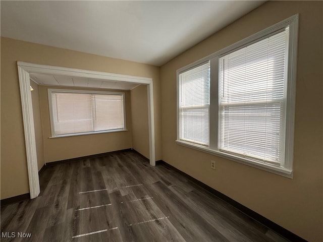 empty room with dark wood finished floors and baseboards