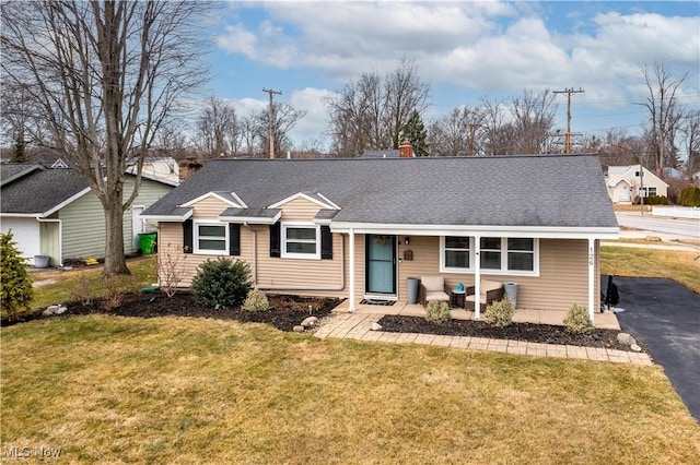 view of front of house with aphalt driveway, a shingled roof, and a front yard