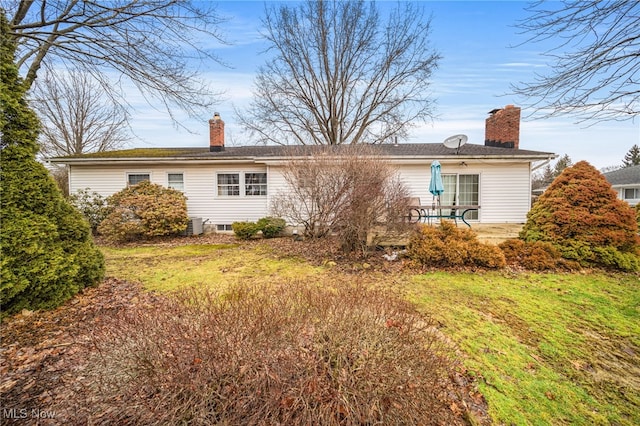 rear view of property with a yard, a chimney, and a patio area